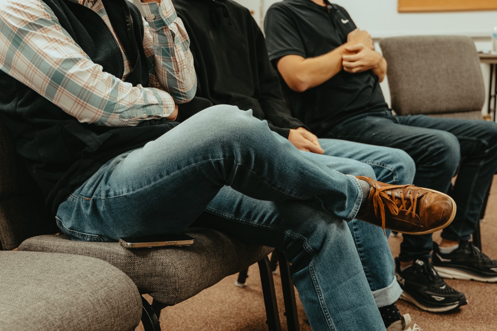 Members of a support group sitting side by side in a circle of chairs