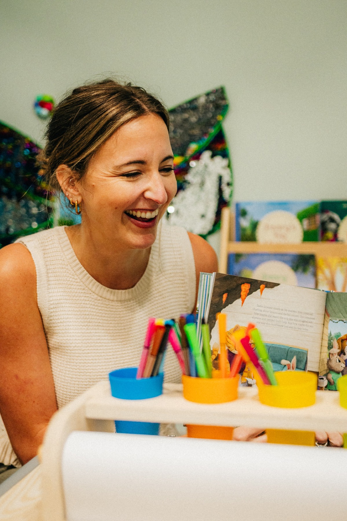 A provider laughing at a table of markers and picture books