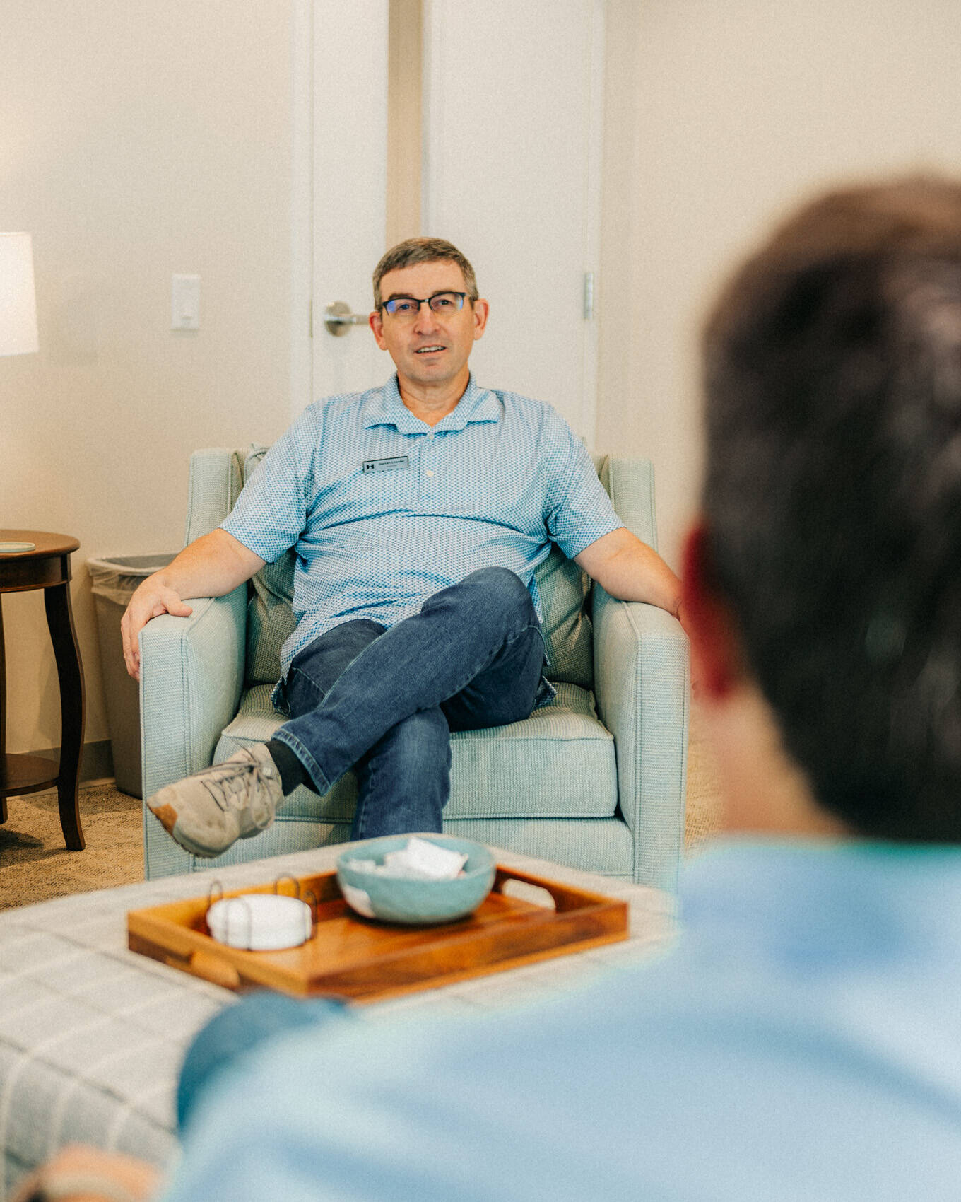 A provider listening to a client from an armchair in his counseling room