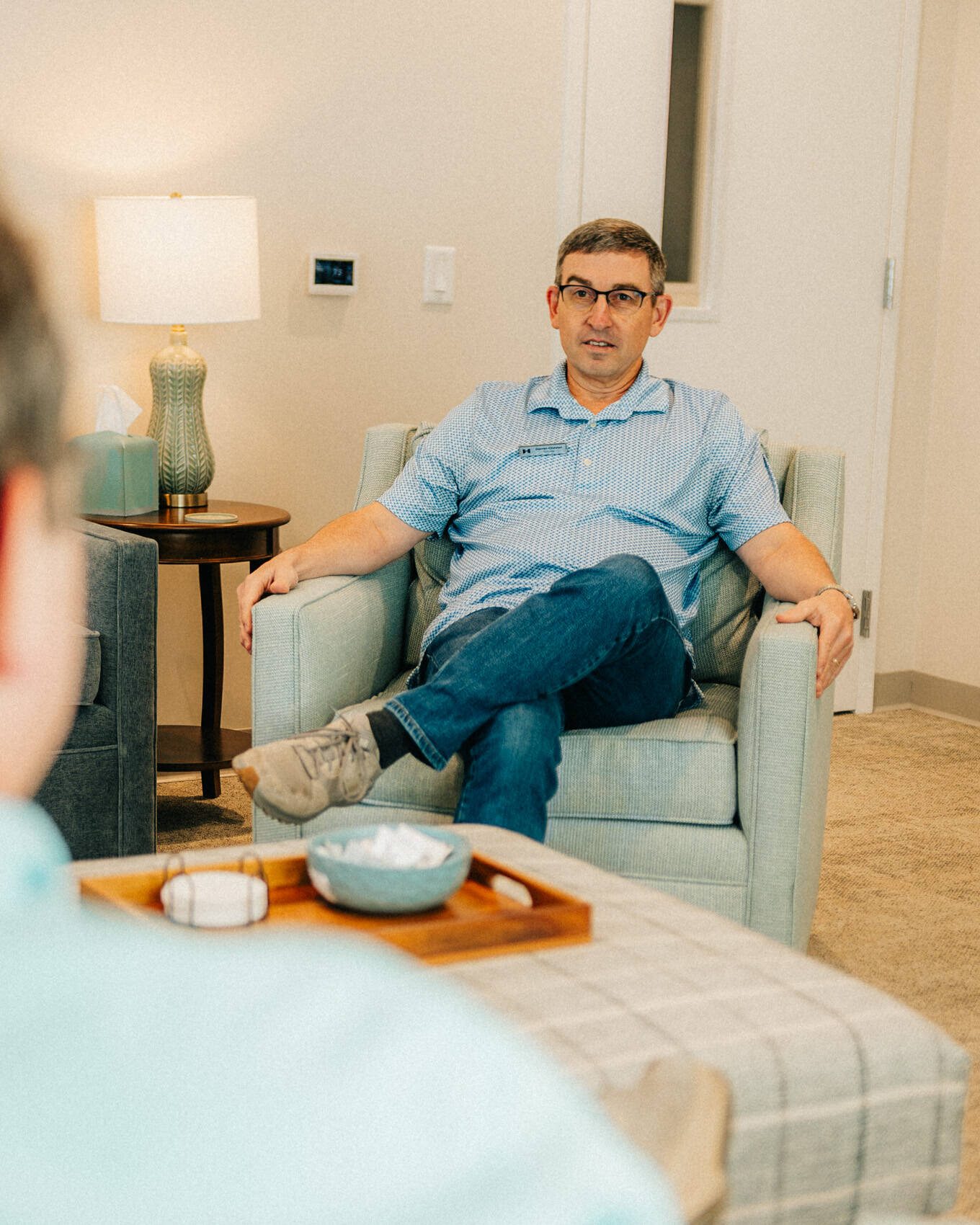 A provider talking with a client from an armchair in his counseling room