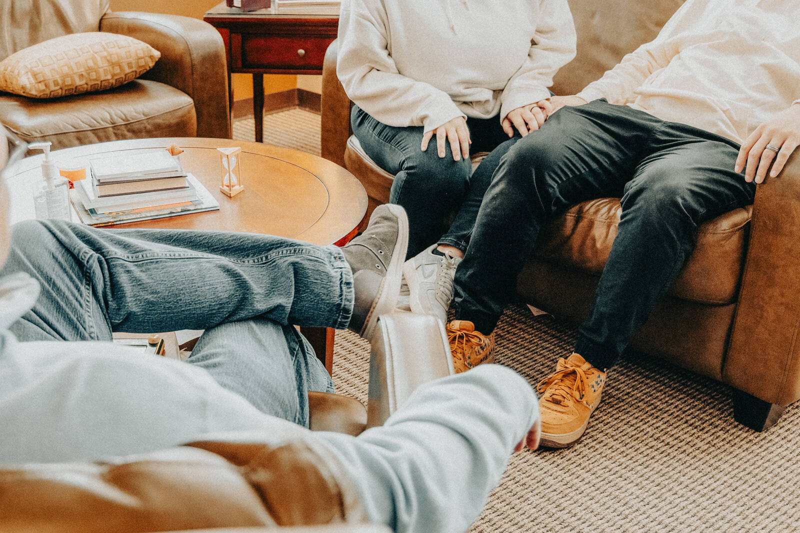 A couple holding hands on a sofa across from their counselor